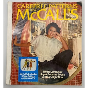 May include: A vintage McCall's sewing pattern magazine cover. The cover features the text "CAREFREE PATTERNS FROM McCall's" in yellow. A woman is wearing a white blouse and dark pants. The magazine also has the text "What's Jumping? Super Summer Looks To Wear Right Now."