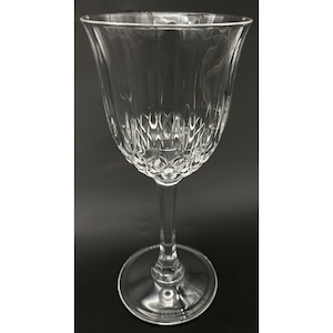 May include: A clear, stemmed wine glass with a decorative, textured bowl and a slender stem. The glass has a wide, flared rim and a round base. The bowl features vertical and diamond-shaped patterns. The glass is made of clear glass.