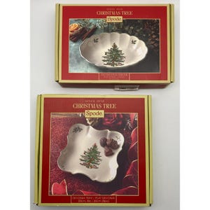 May include: Two Spode Christmas Tree serving dishes in their original boxes. The boxes are red and gold. The dishes are white with a green Christmas tree design. One is an oval serving bowl, and the other is a Devonia tray, 8 inches in diameter.