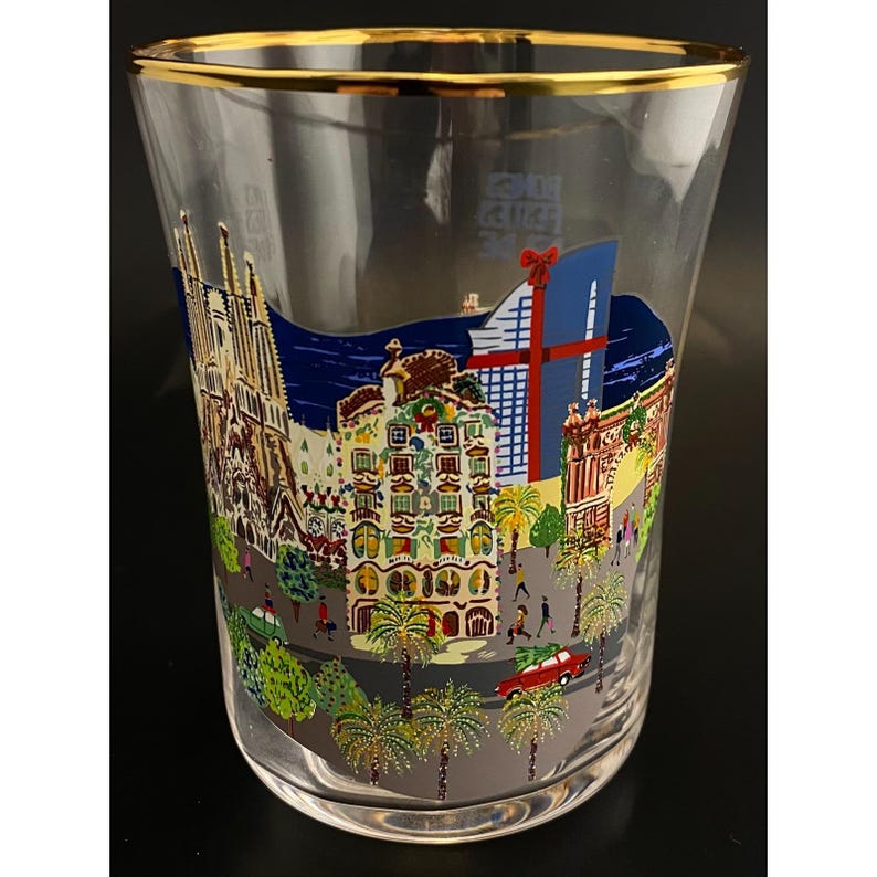 K&ouml;nnte beinhalten: Klares Glas mit Goldrand, verziert mit einer farbenfrohen Illustration von Wahrzeichen Barcelonas. Das Design umfasst die Sagrada Familia, moderne Geb&auml;ude und Palmen, mit einem roten Auto und Fu&szlig;g&auml;ngern.