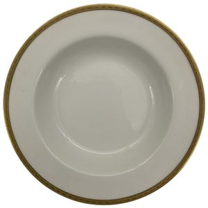 May include: White porcelain soup bowl with a gold rim. The bowl has a wide rim and a deep center. The gold rim features a repeating geometric pattern. This elegant bowl is suitable for formal dining.
