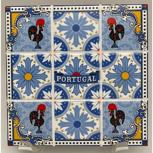 May include: Nine ceramic tiles arranged in a square, featuring a repeating pattern of blue floral designs and stylized roosters. The word "PORTUGAL" is displayed on a banner. The tiles are bordered with blue and yellow decorative elements.
