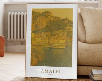 May include: A framed print featuring the Amalfi coast in Italy. The artwork depicts a coastal town with buildings, mountains, and boats, rendered in shades of yellow, green, and blue. The word "AMALFI" and "ITALY" are printed at the bottom.
