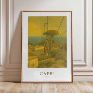 Op de afbeelding: Een ingelijste print met een vintage stijl, met Capri, Italië. De afbeelding toont een persoon op een stoeltjeslift met uitzicht op het eiland. De print heeft een warm, geel getinte kleurenpalet, met de woorden "CAPRI" en "ITALY" onderaan.