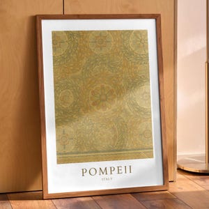 May include: Framed art print featuring a detailed floral pattern in shades of gold, olive, and beige. The print is set in a wooden frame with a white border. The text "POMPEII ITALY" is displayed at the bottom.