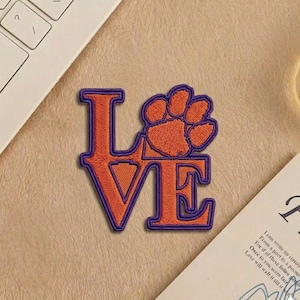 May include: A set of three ceramic mugs with a speckled, cream-colored glaze. Each mug features a different hand-painted floral design in shades of blue, green, and yellow. The mugs have a simple, rounded shape and a comfortable handle.