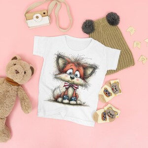 May include: White t-shirt with a cartoon fox illustration in red, white, and blue. The fox wears a bow tie and boots. A brown teddy bear, a camera, a knitted hat, and socks are also in the image, all on a pink background.