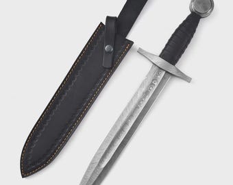 Könnte beinhalten: Ein mittelalterlicher Dolch mit gemusterter Klinge und schwarzem Griff, neben seiner schwarzen Lederscheide. Der Dolch hat einen Parier und einen runden Knauf. Die Scheide hat dekorative Nähte.