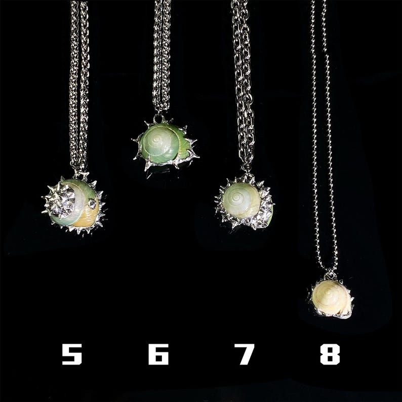 May include: Four silver necklaces with pendant designs. The pendants feature a variety of shell-like shapes in white, green, and yellow, with silver accents. The necklaces are displayed against a black background, with numbers 5, 6, 7, and 8 below.