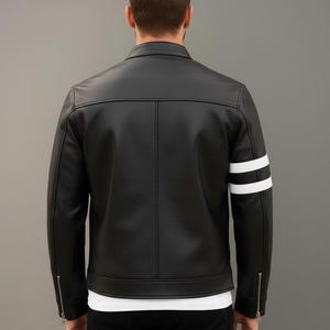 Op de afbeelding: Zwarte leren jas met witte strepen op de mouwen. De jas heeft een klassiek ontwerp met een ritssluiting en een getailleerde pasvorm. Veelzijdige bovenkleding.