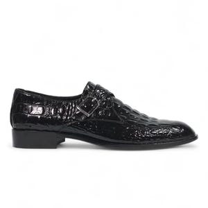 Puede incluir: Zapato negro de charol con textura de piel de cocodrilo. El zapato tiene un cierre de hebilla y un tac&oacute;n bajo. Adecuado para ocasiones formales.