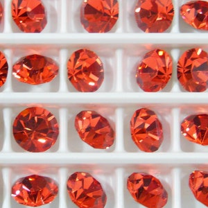 Peut inclure: Vue rapprochée d'un plateau de petits strass ronds de couleur rouge orangé. Les strass sont disposés en rangées et en colonnes, et ils sont tous de la même taille et de la même forme.