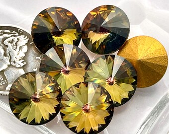 May include: A group of seven round, faceted, iridescent glass rhinestones in shades of green and gold. The rhinestones are arranged in a loose circle on a white, heart-shaped surface.