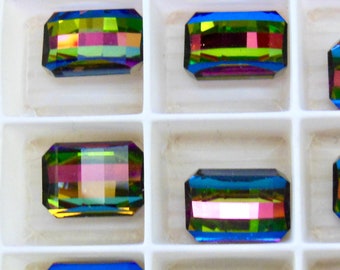 Puede incluir: Surtido de piedras rectangulares de vidrio iridiscente en una caja blanca. Las piedras tienen un efecto arcoíris con tonos de azul, verde y morado.