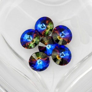 May include: A close-up of six iridescent blue, green, and gold rhinestones in a clear heart-shaped container.