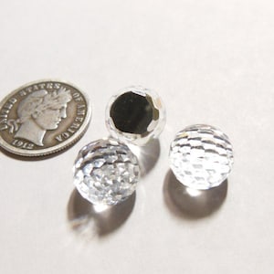 May include: Three clear glass spheres with a faceted design. The spheres are approximately the size of a dime.