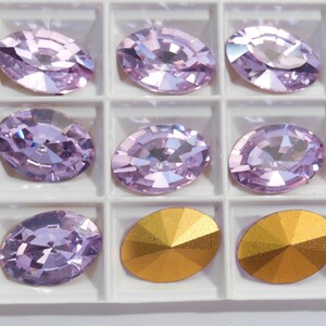 May include: A set of 8 oval-shaped rhinestones in a clear plastic container. The rhinestones are a light purple color and have a faceted design. There are also two gold-colored rhinestones in the container.