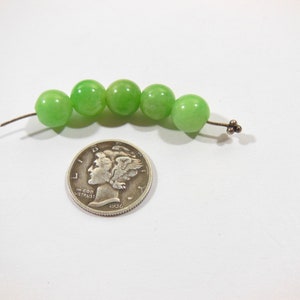 Op de afbeelding: Een streng van zes groene jade kralen geregen aan een zilveren draad met een zilveren sluiting.