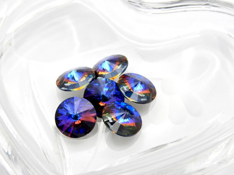 May include: Six iridescent blue round glass rhinestones with a faceted design.