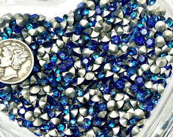 May include: A heart-shaped glass dish filled with blue and silver rhinestones. A silver Mercury dime from 1936 is visible in the corner. The rhinestones are faceted and reflect light, creating a sparkling effect.