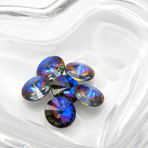 May include: A group of six iridescent blue and purple glass rhinestones in a clear heart-shaped dish.