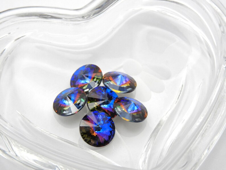 May include: A group of six iridescent blue and purple glass rhinestones in a clear heart-shaped dish.