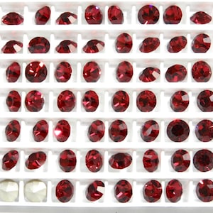 以下が含まれることがあります： 小さな赤い丸いラインストーンのグリッドのクローズアップ。ラインストーンは行と列に配置されており、すべて同じサイズと形です。