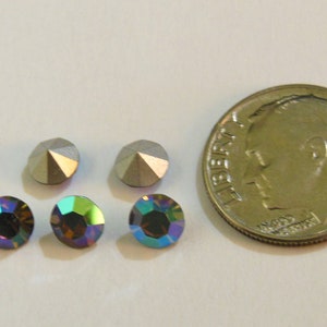 May include: Four iridescent rhinestones, two silver and two blue-green, next to a US dime coin for size comparison.