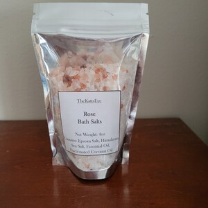 Puede incluir: Una bolsa de cierre herm&eacute;tico plateada llena de sales de ba&ntilde;o rosas del Himalaya. La etiqueta dice "The Katts Eye Rose Bath Salts Net Weight: 4oz Contains: Epsom Salt, Himalayan Sea Salt, Essential Oil, Fractionated Coconut Oil."
