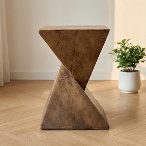 May include: A brown, geometric side table with a unique, twisted design. The table is made of wood and has a triangular shape. The table is approximately 18 inches tall.