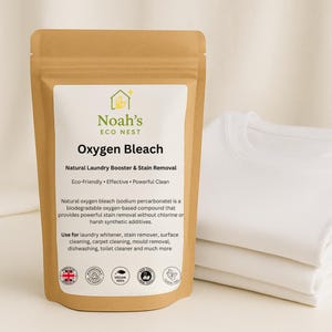 Może przedstawiać: Brązowa papierowa torebka z wybielaczem tlenowym Noah's Eco Nest z białą etykietą. Na etykiecie napisano "Wybielacz tlenowy" i "Naturalny wzmacniacz prania i usuwanie plam". Po prawej stronie stos białych koszulek.