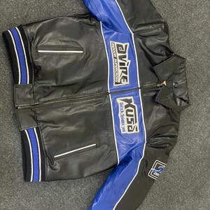 以下が含まれることがあります： 黒い革のジャケットで、青と白のアクセントが付いています。 ジャケットはジッパー開閉、2つのフロントポケット、リブ編みの袖口と裾が特徴です。 ジャケットには「Evire Indoor Supercross」と「Kusa Black Spider 310」の文字がプリントされています。