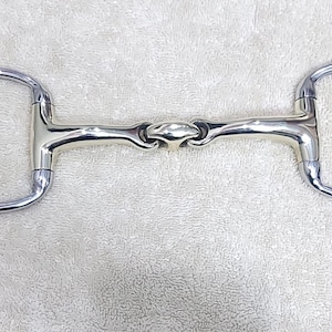 Op de afbeelding: Een gepolijste zilveren D-ring paardenbit. De bit heeft een centraal gewricht en twee cirkelvormige ringen, elk met een diameter van ongeveer 12,7 cm. Het metaal heeft een reflecterend oppervlak en de bit is ontworpen voor paardensport.