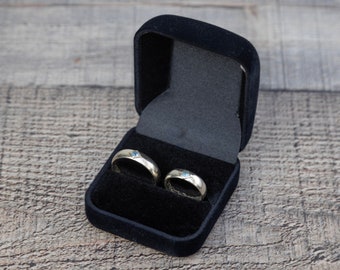 May include: Two gold rings with blue gemstones inside a black velvet ring box.