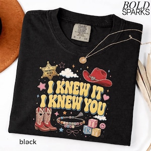 Może przedstawiać: Czarny t-shirt z nadrukiem graficznym z ż&oacute;łtym napisem I KNEW IT I KNEW YOU. Wz&oacute;r zawiera czerwony kowbojski kapelusz, parę kowbojek, gwiazdę szeryfa, bransoletkę z koralik&oacute;w, klocki z literami oraz małe gwiazdki i chmurki na czarnym tle.