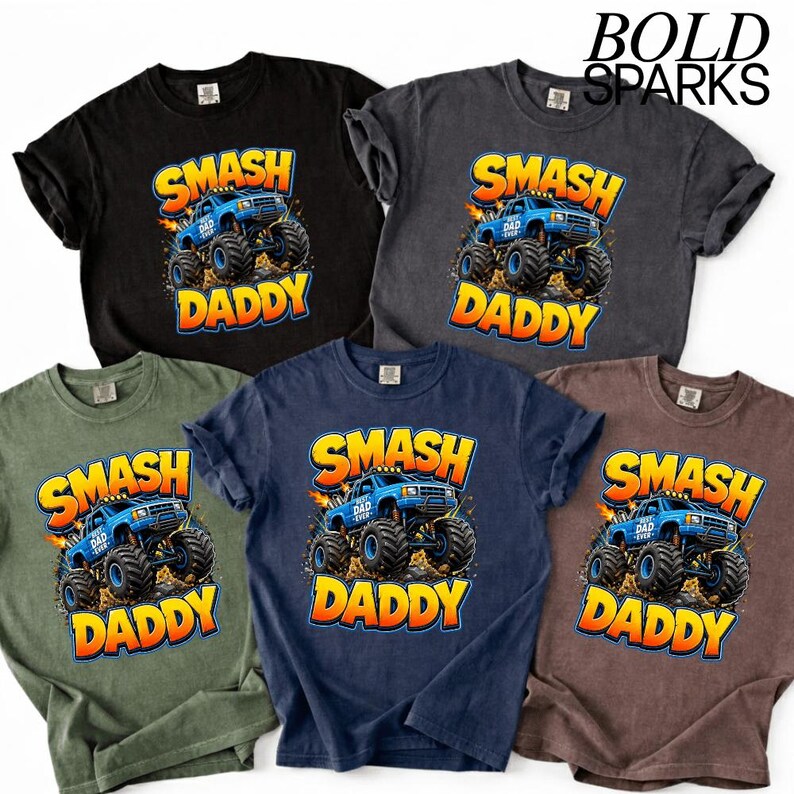May include: A collection of five short-sleeved t-shirts in various colors, each featuring a graphic of a blue monster truck with the words "SMASH DADDY" in a bold, orange font. The shirts are black, gray, olive green, navy blue, and brown.