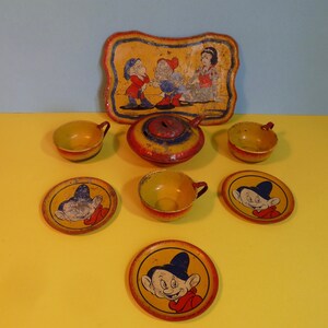 Puede incluir: Un juego de t&eacute; de hojalata vintage con Blancanieves y los Siete Enanitos. El juego incluye una tetera, cuatro tazas, cuatro platillos y una bandeja con una imagen de Blancanieves y dos enanos. El juego est&aacute; pintado en colores brillantes, incluyendo rojo, amarillo, azul y verde.