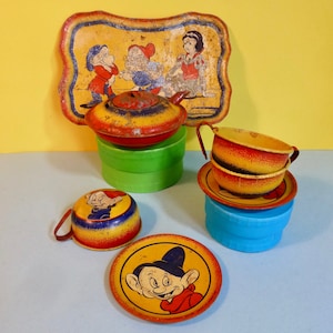 Puede incluir: Juego de t&eacute; de juguete de hojalata vintage con Blancanieves y los Siete Enanitos. El juego incluye una tetera, dos tazas, dos platillos y una bandeja. La tetera y las tazas est&aacute;n decoradas con im&aacute;genes de los enanitos, mientras que la bandeja presenta a Blancanieves y dos enanitos. El juego est&aacute; en buen estado con algunas se&ntilde;ales de desgaste.