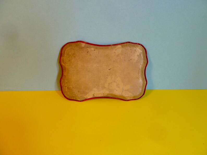 May include: A rectangular tray with a red rim and a light brown, slightly textured surface. The tray is empty.