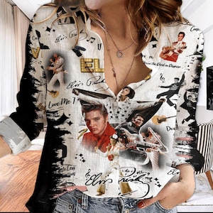 May include: White button-down shirt featuring multiple images of Elvis Presley, musical notes, and the text "Elvis Presley". The shirt has long sleeves with black accents and a collared neckline. The design includes various poses of Elvis.