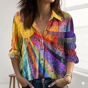 May include: A colourful patchwork shirt with a button-down front. The design includes a sunburst pattern in yellow, orange, red, and purple hues. The long-sleeved shirt has a collared neckline and is made of a soft material.