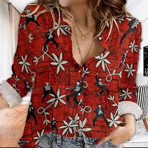 May include: Red button-down shirt with a repeating pattern of stylized figures in black and white, interspersed with white floral and geometric designs. The shirt has long sleeves and is made of a lightweight fabric.