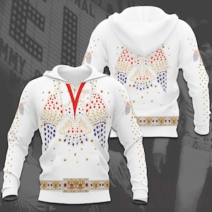 May include: White hoodie with a design of red, blue, and gold embellishments. The front features a V-shaped design, and the back has a similar pattern. The sleeves and hood are also decorated with embellishments. A belt-like design is at the bottom.