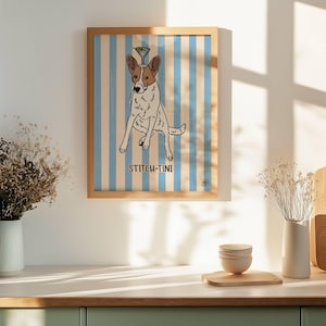 May include: A framed wall art print featuring a white and brown dog with a martini glass balanced on its head, set against a light blue and white vertical striped background with the text STITCH-TINI printed in black below the dog.