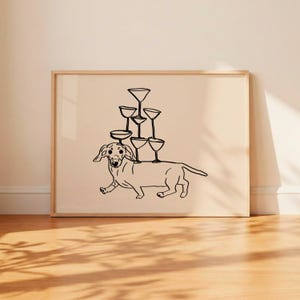 May include: A framed wall art print featuring a black line drawing of a dachshund dog with a stack of six martini glasses balanced on its back. The illustration is rendered in black ink on a solid light beige background within a wooden frame.