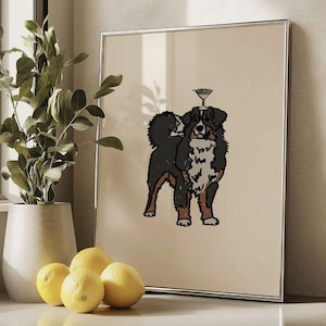 May include: A framed wall art print featuring a stylized illustration of a Bernese Mountain Dog with a martini glass balanced on its head. The dog has black, white, and brown fur, and the background of the print is a solid light beige color.