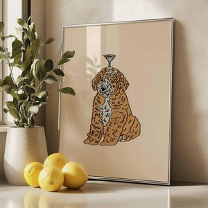 May include: A framed wall art print featuring a line-art illustration of a golden-brown curly-haired dog sitting down with a martini glass balanced on its head, set against a solid light beige background within a thin silver frame.