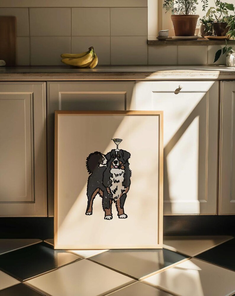 May include: A framed print featuring a stylized illustration of a Bernese Mountain Dog with a martini glass balanced on its head. The dog has black, white, and brown fur, and the artwork is set against a solid cream-colored background.