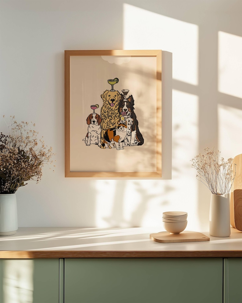 May include: A framed wall art print featuring a group of three dogs and one cat. The animals are illustrated in a cartoon style, with two dogs balancing small cocktail glasses on their heads. The background of the print is a solid light beige colour.