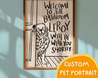 May include: A framed wall art print featuring a black line drawing of a shaggy dog peeking from behind a door. The text reads: WELCOME TO THE BATHROOM LEROY WILL BE WITH YOU SHORTLY. The print is set in a dark brown wooden frame against a light blue wall.